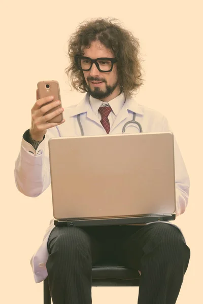 Šťastný muž lékař usmívá při používání mobilního telefonu s notebookem — Stock fotografie