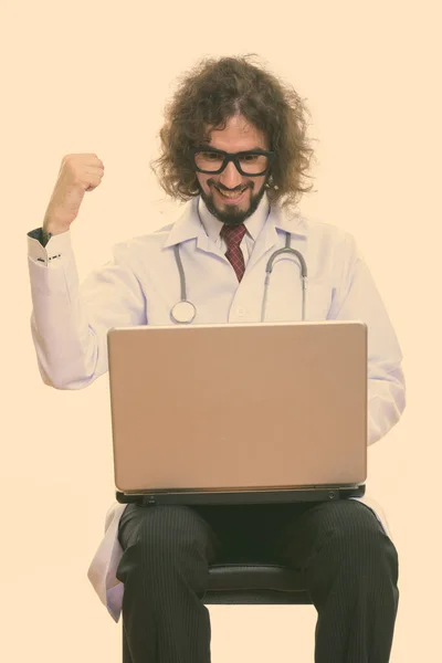 Студийный снимок счастливого человека доктор улыбается при использовании ноутбука с поднятым кулаком — стоковое фото