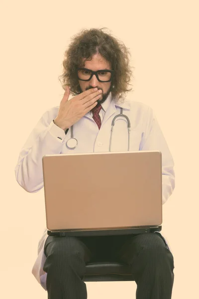 Studio záběr pohledný muž lékař pomocí notebooku vypadá šokován — Stock fotografie