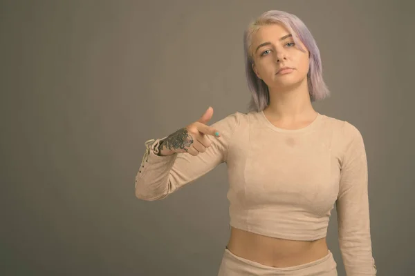 Junge schöne Rebellin mit bunten Haaren vor grauem Hintergrund — Stockfoto