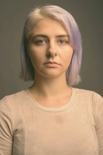 Jovem bela mulher rebelde com cabelo colorido contra fundo cinza — Fotografia de Stock