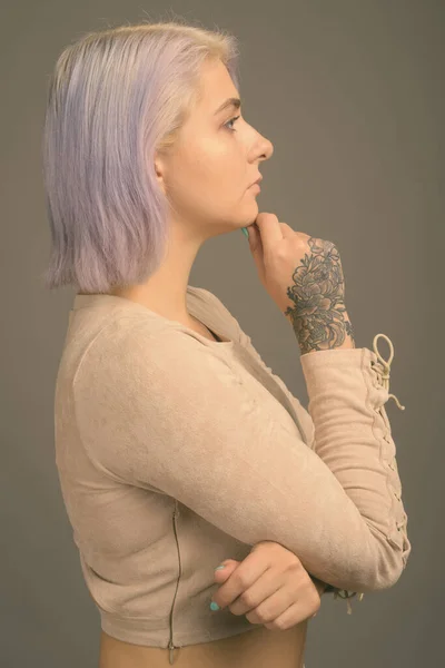 Junge schöne Rebellin mit bunten Haaren vor grauem Hintergrund — Stockfoto