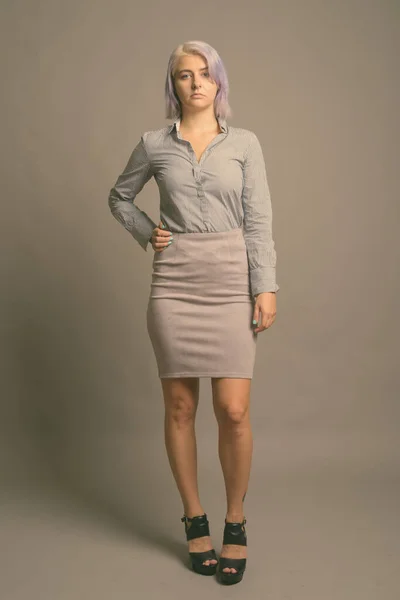 Junge schöne Geschäftsfrau mit kurzen bunten Haaren vor grauem Hintergrund — Stockfoto