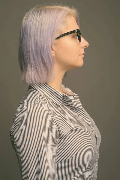 Jovem mulher de negócios bonita com cabelo colorido curto contra fundo cinza — Fotografia de Stock
