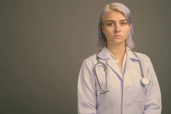 Joven hermosa mujer médico con pelo corto y colorido sobre fondo gris —  Fotos de Stock