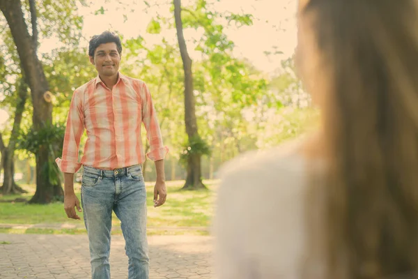 Hombre indio feliz sonriendo y de pie mientras mira a la hermosa mujer enamorada en el tranquilo parque verde — Foto de Stock