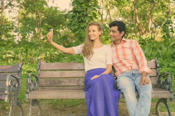Szczęśliwy wieloetniczne para biorąc selfie razem i w miłości w spokojnym zielony park — Zdjęcie stockowe