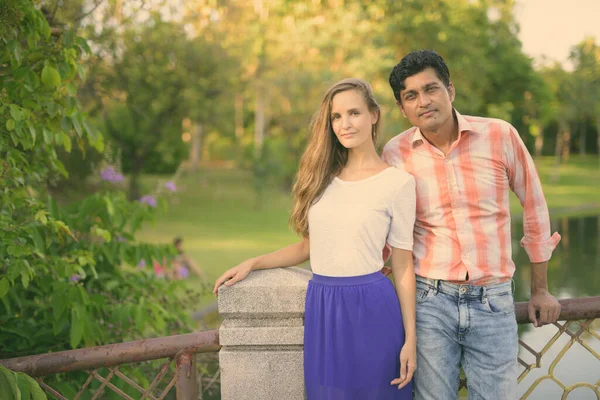 Pareja multiétnica de pie juntos en el puente del tranquilo parque verde — Foto de Stock