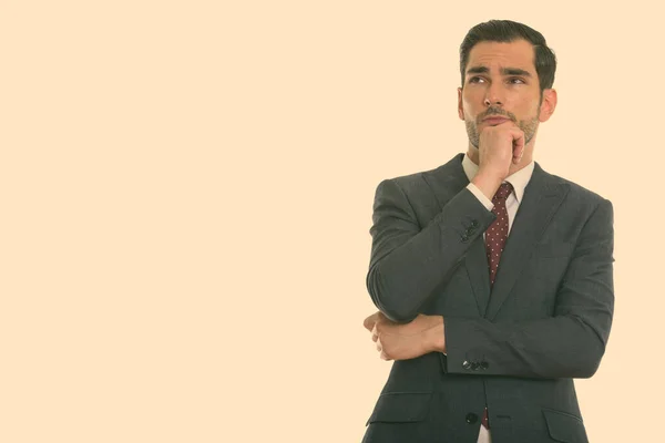 Studio shot of young handsome businessman thinking while looking up — Stock Photo, Image