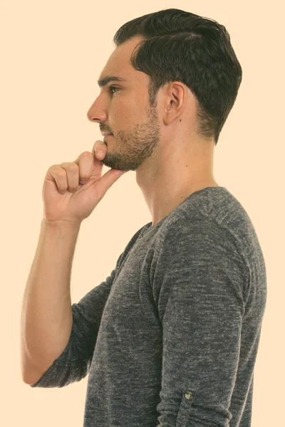 Profile view of young handsome man thinking with hand on chin — Stock Photo, Image
