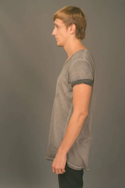 Junger schöner Mann mit blonden Haaren vor grauem Hintergrund — Stockfoto