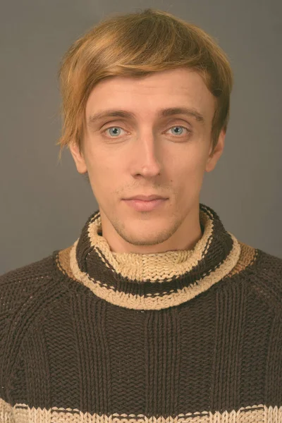 Junger schöner Mann mit blonden Haaren vor grauem Hintergrund — Stockfoto