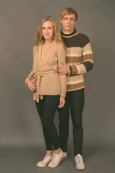 Studio shot of young couple together against gray background — Stock Photo, Image
