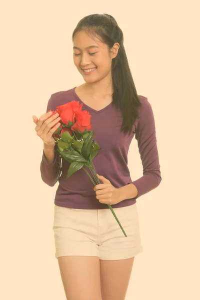 年轻快乐的亚洲少女笑着捧着红玫瑰迎接情人节 — 图库照片