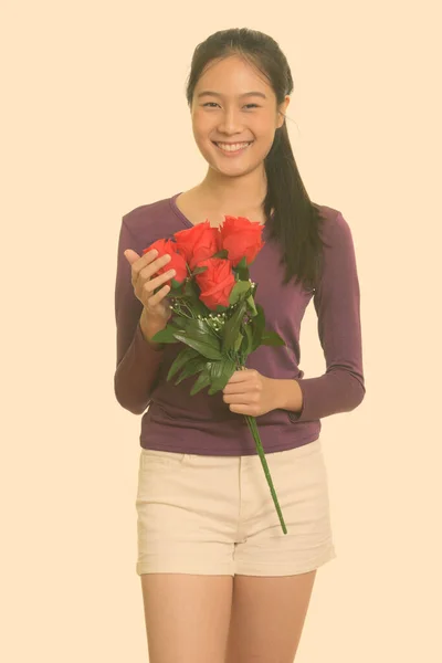 年轻快乐的亚洲少女笑着捧着红玫瑰迎接情人节 — 图库照片