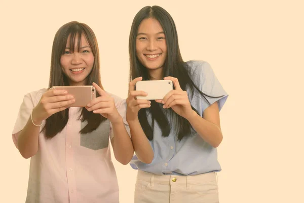 Dos jóvenes feliz asiático adolescente niñas sonriendo y tomando foto con el teléfono móvil — Foto de Stock