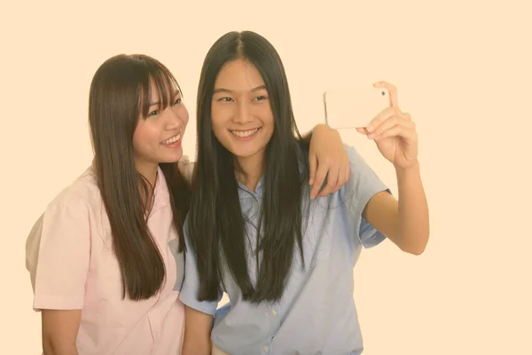행복 한 아시아 십 대 소녀 두 명 이웃으면서 핸드폰으로 셀카를 찍고 있다 — 스톡 사진