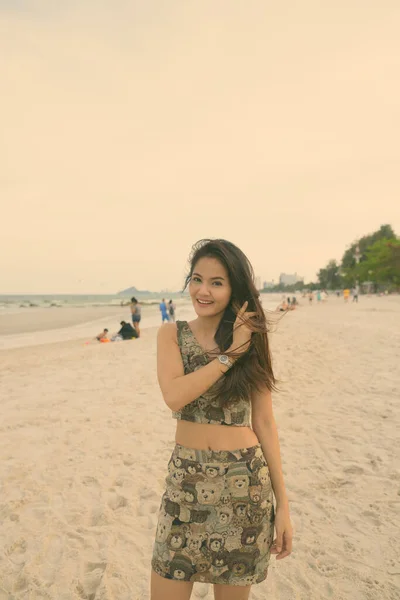 Joven feliz hermosa mujer asiática sonriendo y de pie en la orilla de la playa pública en Hua Hin Tailandia —  Fotos de Stock