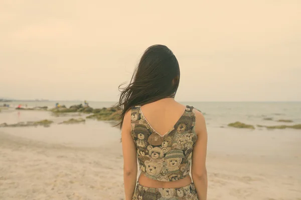 Achteraanzicht van jonge Aziatische vrouw op zoek naar schilderachtig uitzicht op het openbare strand in Hua Hin Thailand — Stockfoto