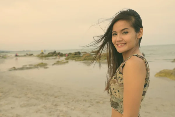 Mladá šťastná krásná asijská žena se usmívá na veřejné pláži Hua Hin v Thajsku — Stock fotografie