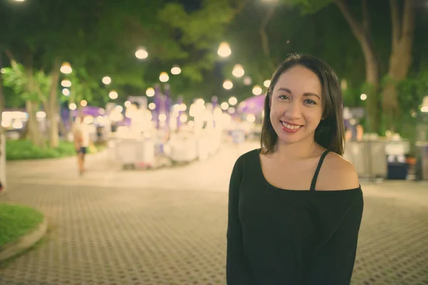 Молода щаслива жінка з Азії посміхається проти мальовничого погляду на нічний ринок у Хуа Хін Таїланді — стокове фото