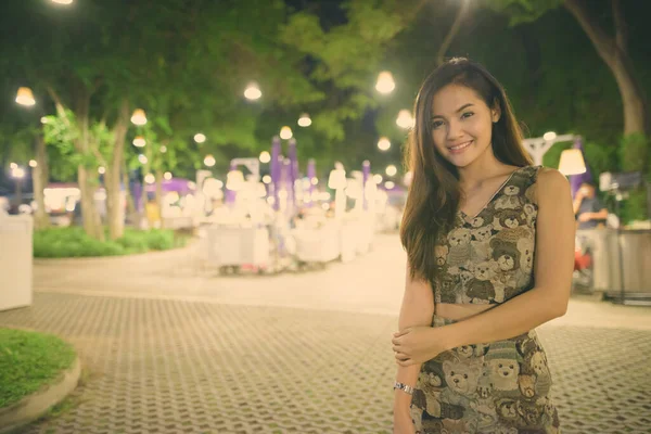 Fiatal boldog gyönyörű ázsiai nő mosolyog festői kilátás nyílik az éjszakai piac Hua Hin Thaiföldön — Stock Fotó
