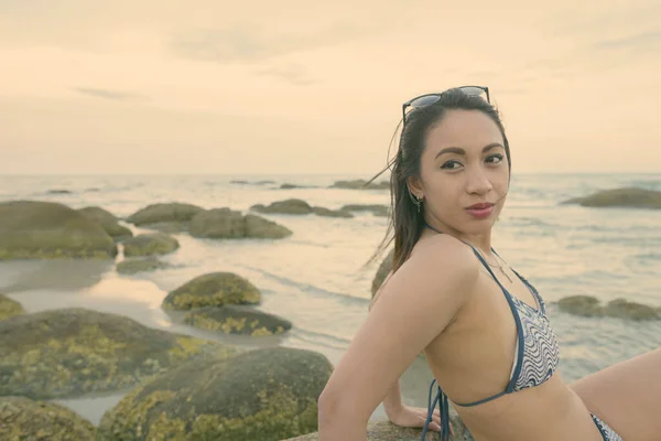 สาวสวยเอเชียคิดว่าขณะที่นั่งบนหินของชายหาดสาธารณะในหัวหิน ประเทศไทย — ภาพถ่ายสต็อก