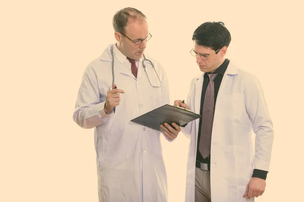成熟的男医生和年轻男医生这两种写作放在剪贴板上 — 图库照片