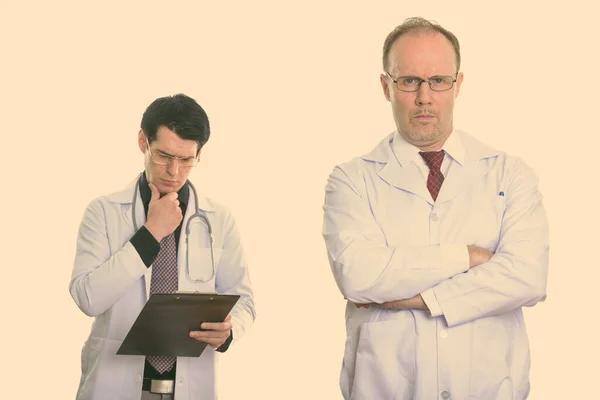 Mature Man Doctor Arms Crossed Young Man Doctor Reading Clipboard — Stock Photo, Image