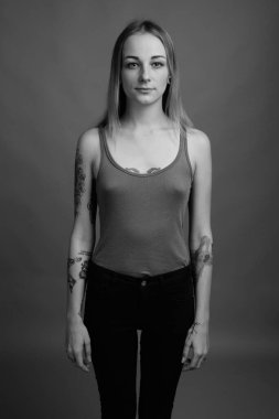 Studio shot of young beautiful rebellious woman with dyed hair against gray background in black and white