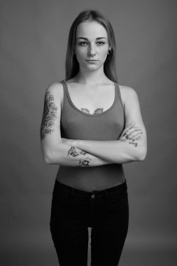 Studio shot of young beautiful rebellious woman with dyed hair against gray background in black and white