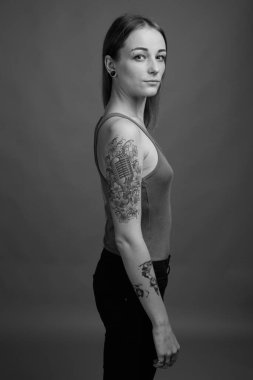 Studio shot of young beautiful rebellious woman with dyed hair against gray background in black and white