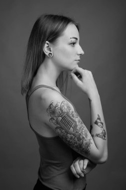 Studio shot of young beautiful rebellious woman with dyed hair against gray background in black and white