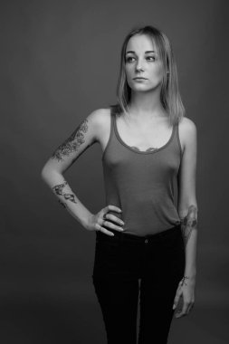 Studio shot of young beautiful rebellious woman with dyed hair against gray background in black and white