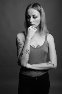 Studio shot of young beautiful rebellious woman with dyed hair against gray background in black and white