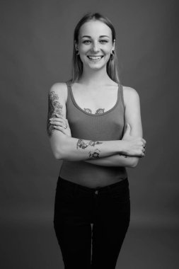 Studio shot of young beautiful rebellious woman with dyed hair against gray background in black and white