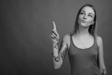 Studio shot of young beautiful rebellious woman with dyed hair against gray background in black and white