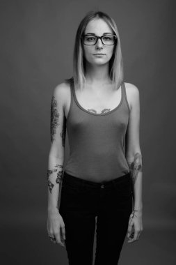 Studio shot of young beautiful rebellious woman with dyed hair against gray background in black and white