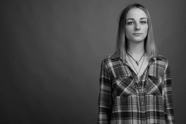 Studio shot of young beautiful rebellious woman with dyed hair against gray background in black and white