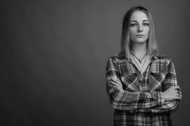 Studio shot of young beautiful rebellious woman with dyed hair against gray background in black and white