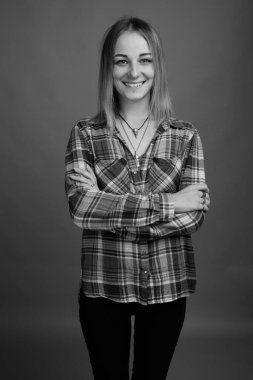 Studio shot of young beautiful rebellious woman with dyed hair against gray background in black and white