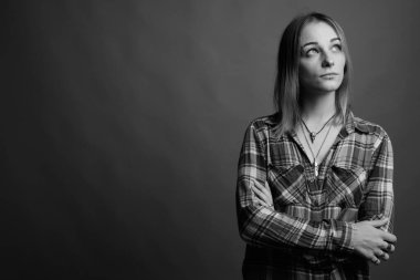 Studio shot of young beautiful rebellious woman with dyed hair against gray background in black and white