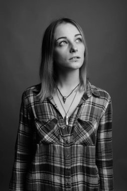 Studio shot of young beautiful rebellious woman with dyed hair against gray background in black and white