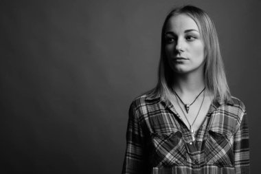 Studio shot of young beautiful rebellious woman with dyed hair against gray background in black and white