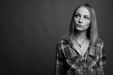 Studio shot of young beautiful rebellious woman with dyed hair against gray background in black and white