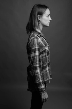Studio shot of young beautiful rebellious woman with dyed hair against gray background in black and white