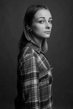 Studio shot of young beautiful rebellious woman with dyed hair against gray background in black and white