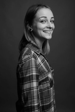 Studio shot of young beautiful rebellious woman with dyed hair against gray background in black and white