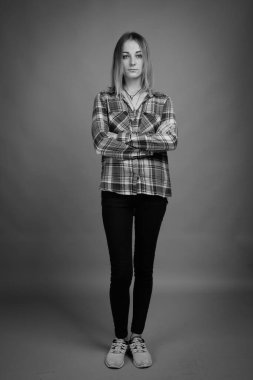 Studio shot of young beautiful rebellious woman with dyed hair against gray background in black and white