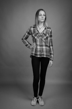 Studio shot of young beautiful rebellious woman with dyed hair against gray background in black and white
